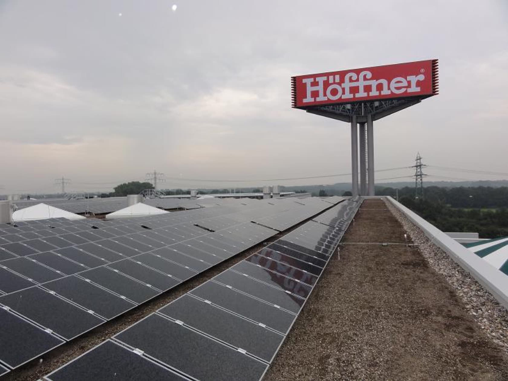 Modulreihen auf dem Hallendach, dahinter der rote Höffner-Werbepylon